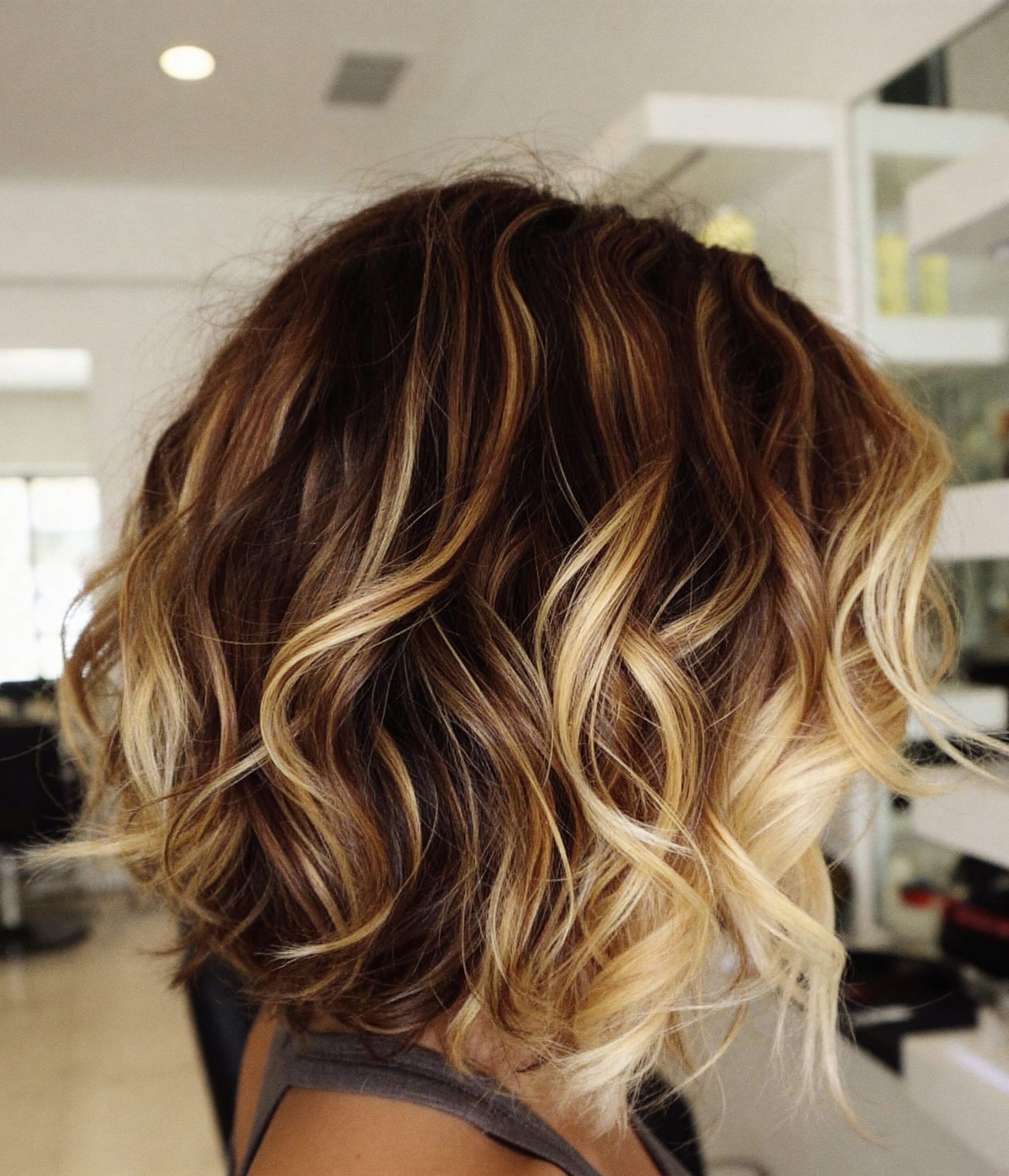 layered bob haircut with natural waves and warm brunette tones at Numi Hair Salon