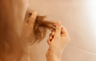 Woman holding damaged hair with split ends between her fingers