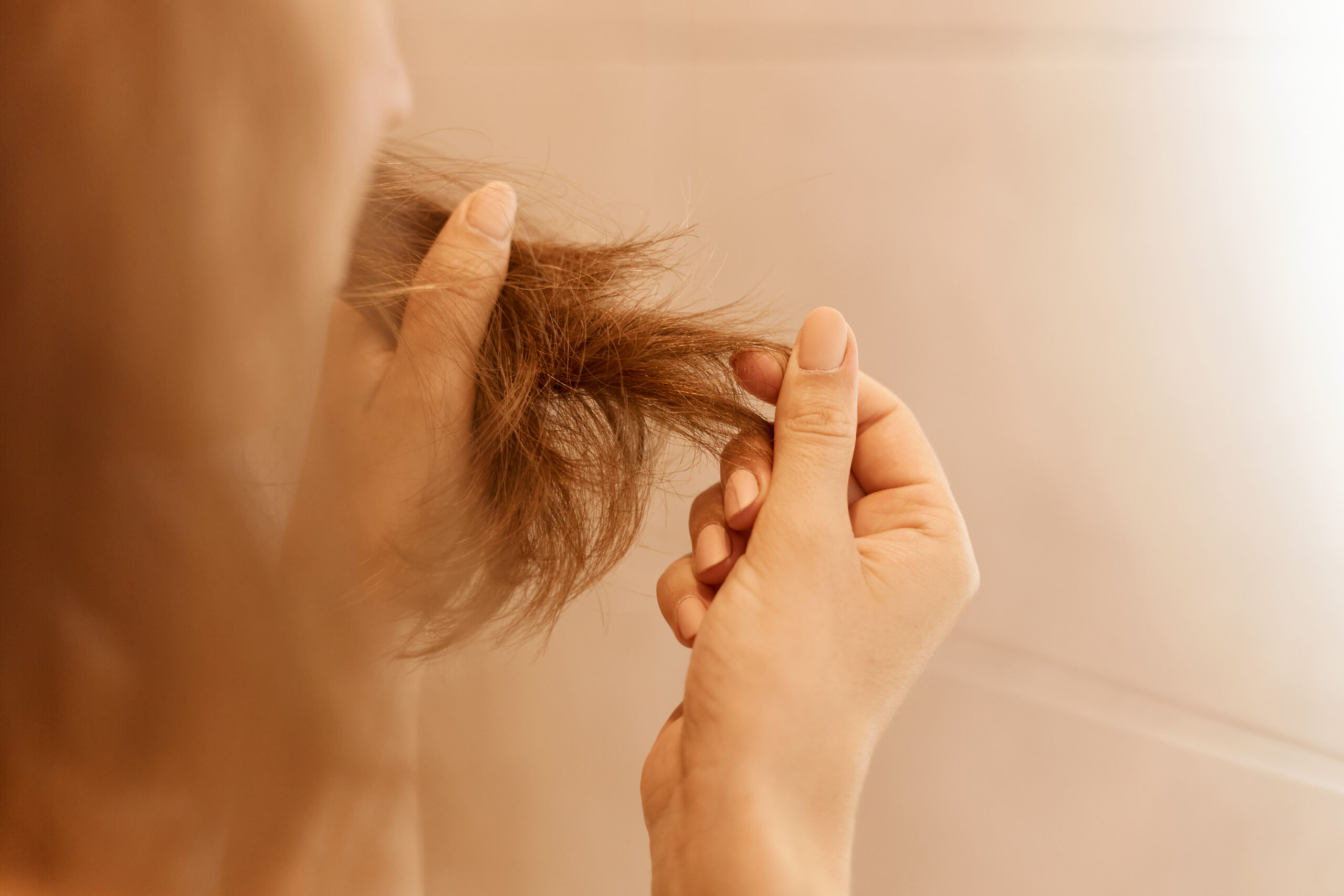 Woman holding damaged hair with split ends between her fingers