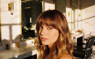 Woman with curtain bangs and balayage highlights styled with soft waves at a luxury hair salon in Scarsdale NY