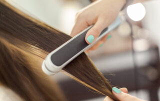 close up photo of friend using flat iron on hair potentially damaging in scarsdale ny