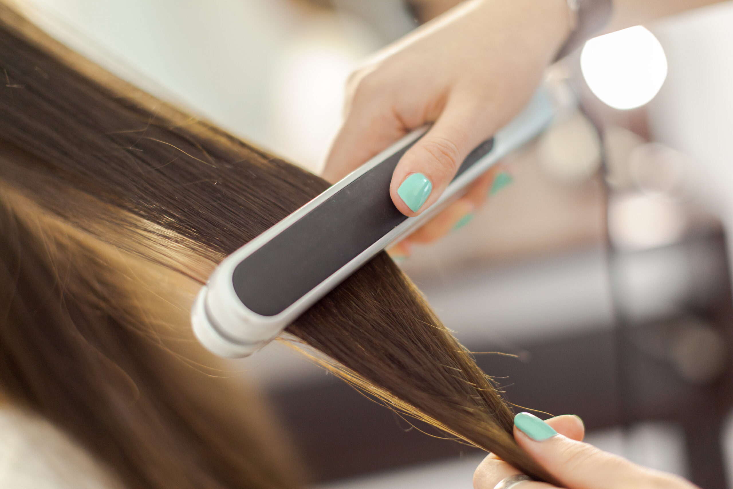 close up photo of friend using flat iron on hair potentially damaging in scarsdale ny