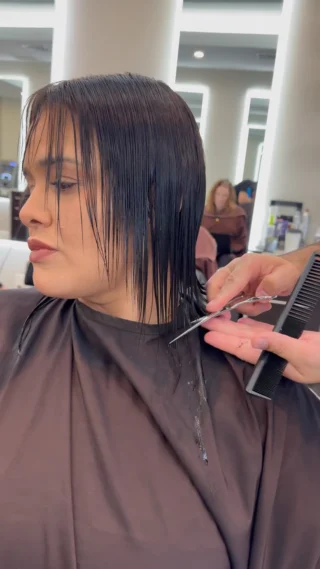 Stylist cutting a client's wet bob in the salon
