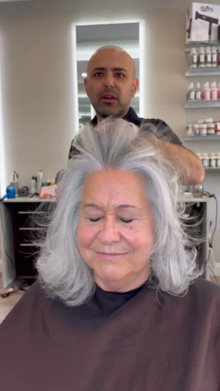 Stylist styling a client's gray hair at the salon