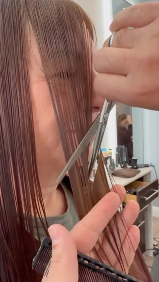 Stylist cutting a client's fringe with scissors
